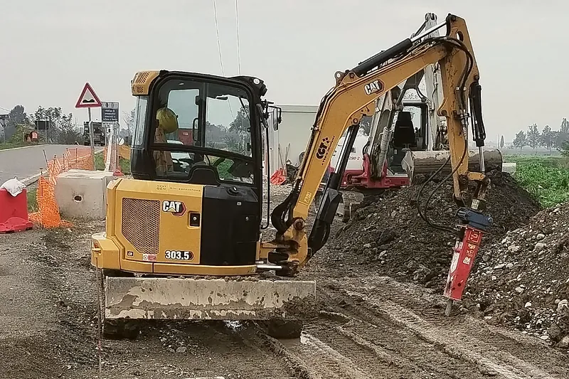 Miniescavatore Caterpillar 303.5 CR con martello demolitore Promove durante la demolizione del fondo per la posa di plinti prefabbricati