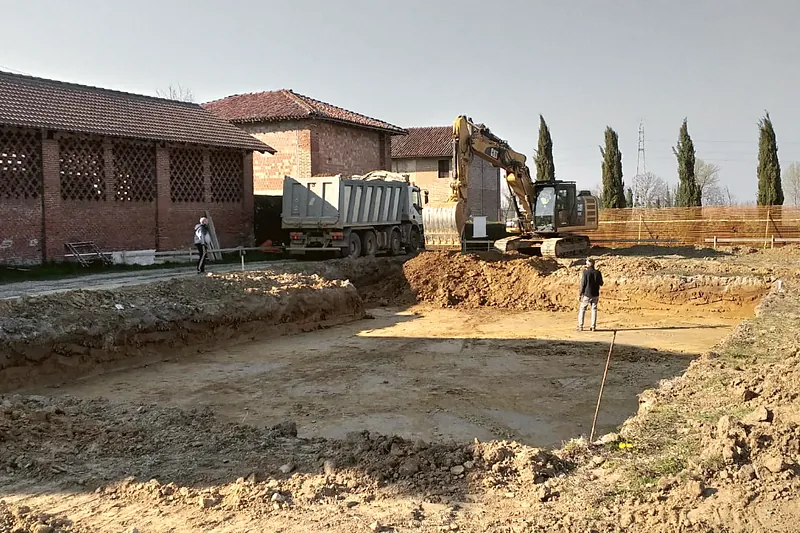 Scavo di fondazione con escavatore Caterpillar e camion in caricamento su un cantiere edile